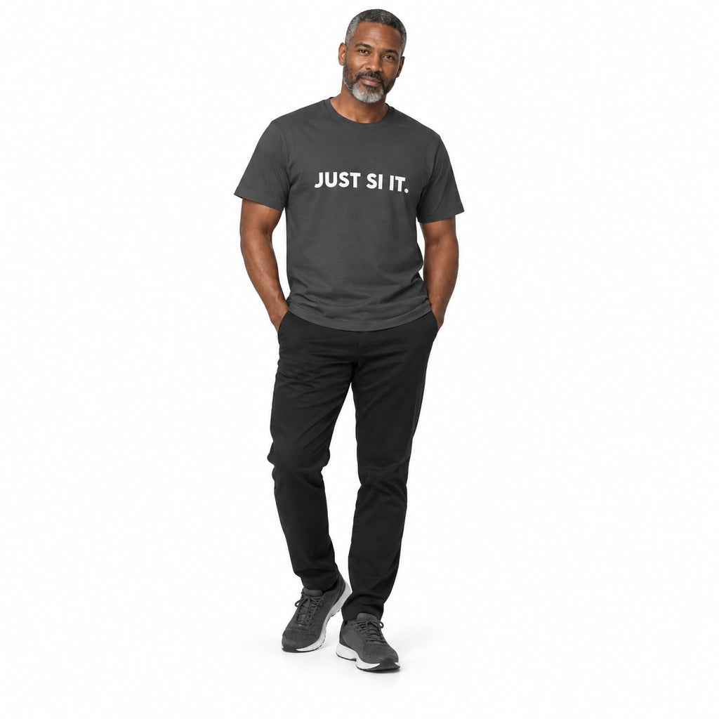 Full-body man wearing the asphalt JUST SI IT. t-shirt with white chest lettering and grey trainers, hands in trouser pockets on a white background.