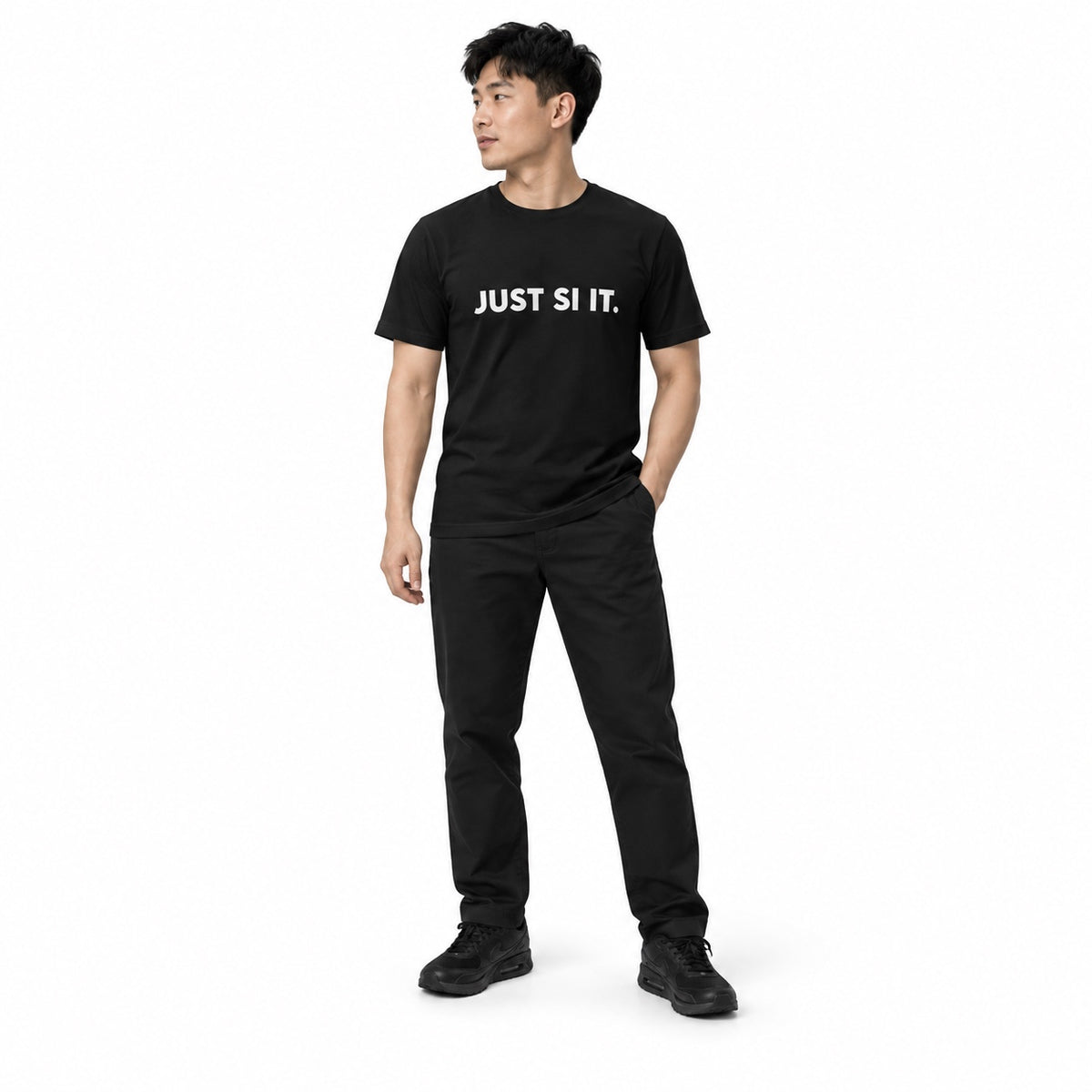 Full-body man wearing the black JUST SI IT. t-shirt with white chest lettering and black trainers, looking to the side on a white background.