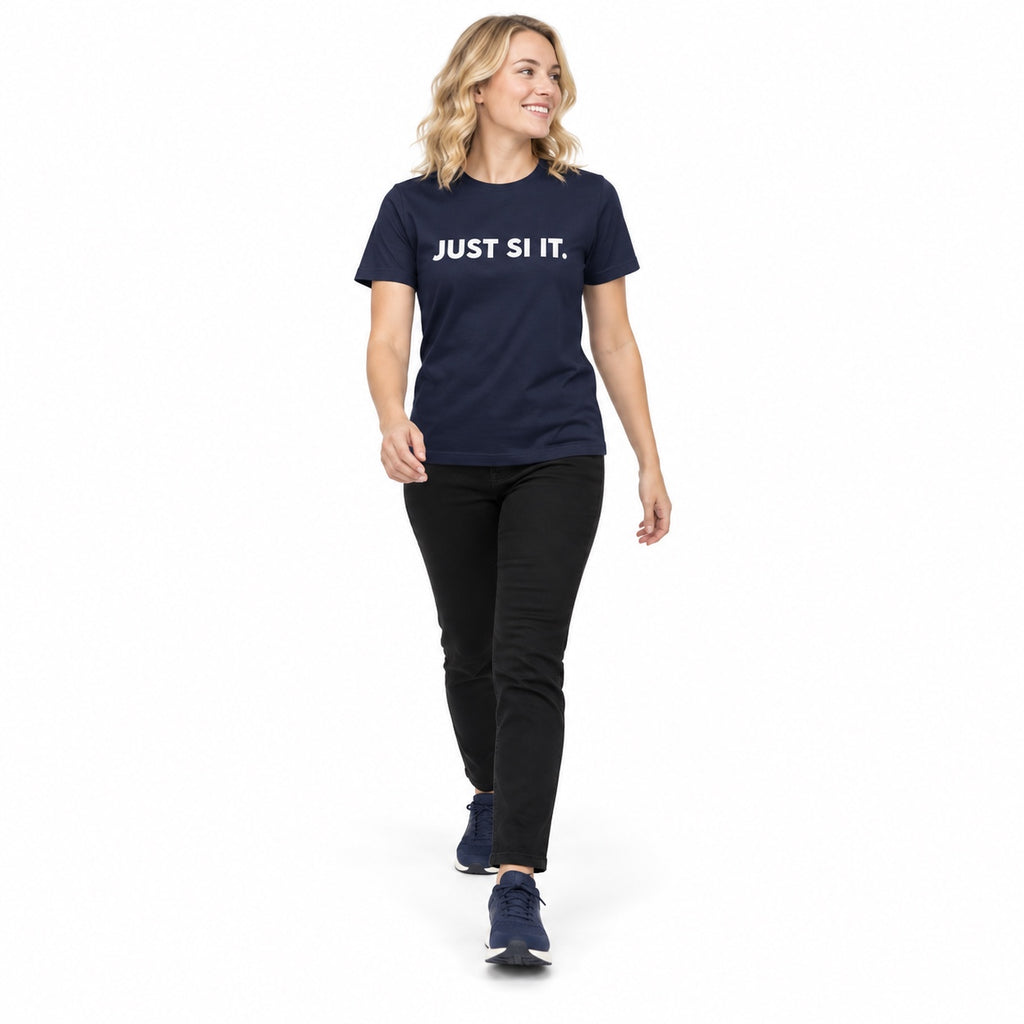 Full-body blonde woman wearing the navy JUST SI IT. t-shirt with white chest lettering and navy trainers, stepping forward on a white background.