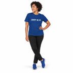 Full-body woman wearing the true royal JUST SI IT. t-shirt with white chest lettering and blue trainers, hand on hip on a white background.