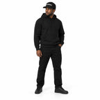 Full-body model wearing the black MAKE NO MISTAKES. embroidered cap with matching black hoodie and shoes, one hand in his pocket on a white background.