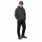 Full-body model wearing the dark grey MAKE NO MISTAKES. embroidered cap with a matching charcoal hoodie and shoes, hands in pockets on a white background.
