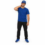 Full-body model wearing the royal blue MAKE NO MISTAKES. embroidered cap with matching blue T-shirt and shoes, smiling with a hand behind his neck on white.