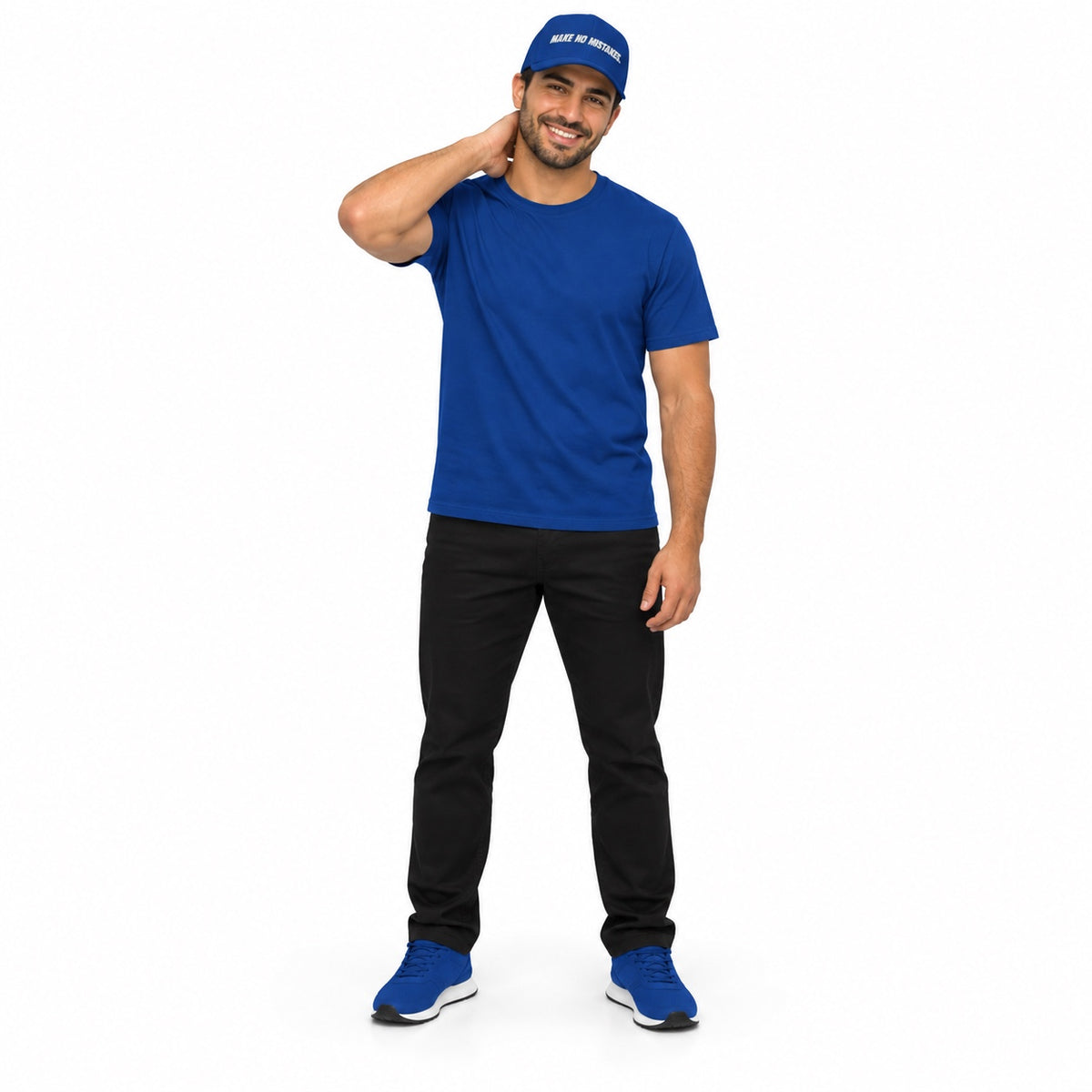Full-body model wearing the royal blue MAKE NO MISTAKES. embroidered cap with matching blue T-shirt and shoes, smiling with a hand behind his neck on white.