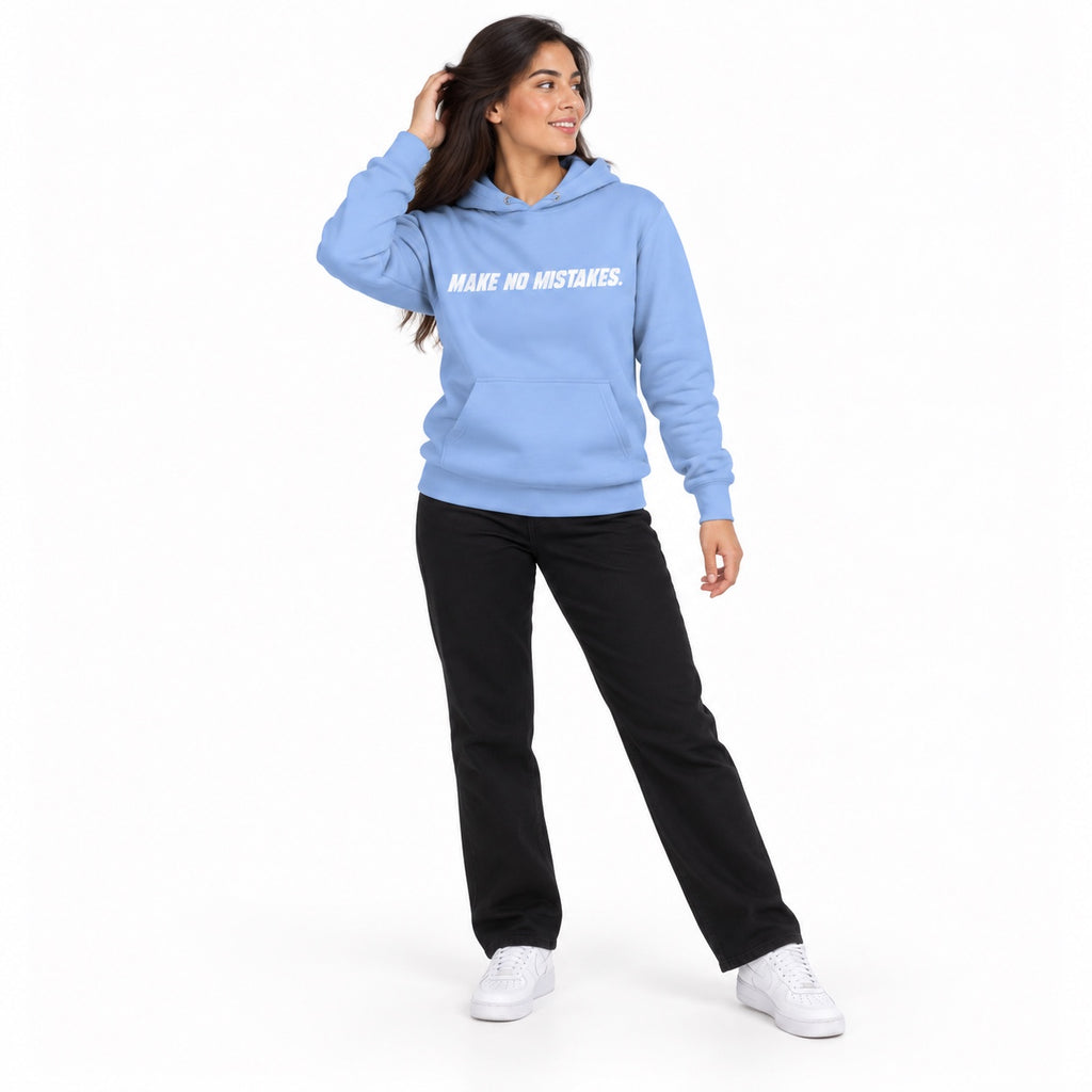 Full-body model wearing the Carolina blue MAKE NO MISTAKES. hoodie with white chest print, touching her hair and looking aside on a plain white background.