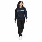Full-body model wearing the navy blazer MAKE NO MISTAKES. hoodie with white chest print, stepping forward with relaxed arms on a plain white background.
