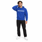 Full-body model wearing the team royal blue MAKE NO MISTAKES. hoodie with white chest print, smiling with one hand behind his neck on a plain white background.