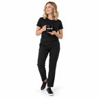 Full-body blonde model in black clothing holding the black MAKE NO MISTAKES. mug with its white print facing forward, looking aside on a plain white background.