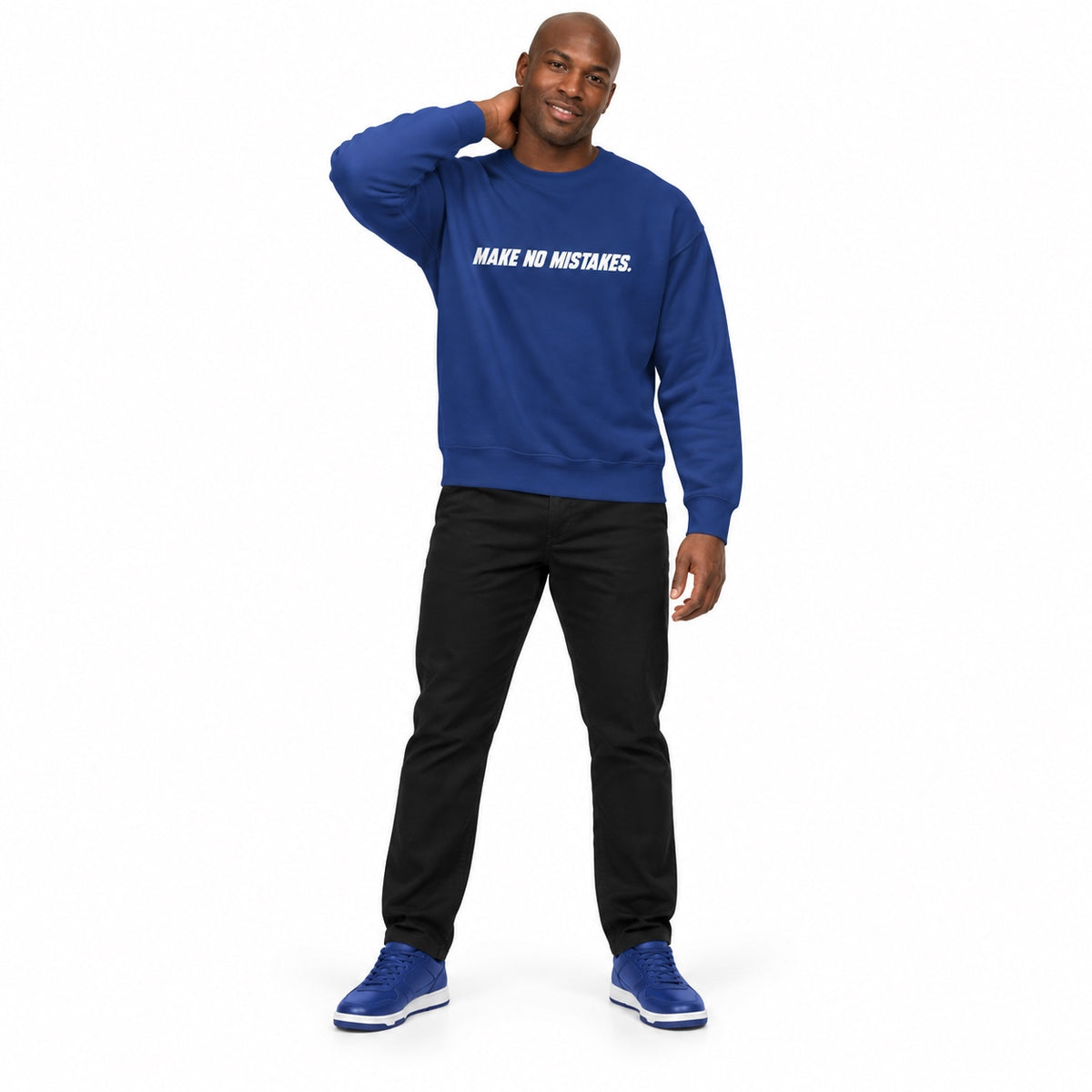 Full-body man wearing the team royal MAKE NO MISTAKES. sweatshirt with white chest print and blue trainers, hand behind his neck on a white background.