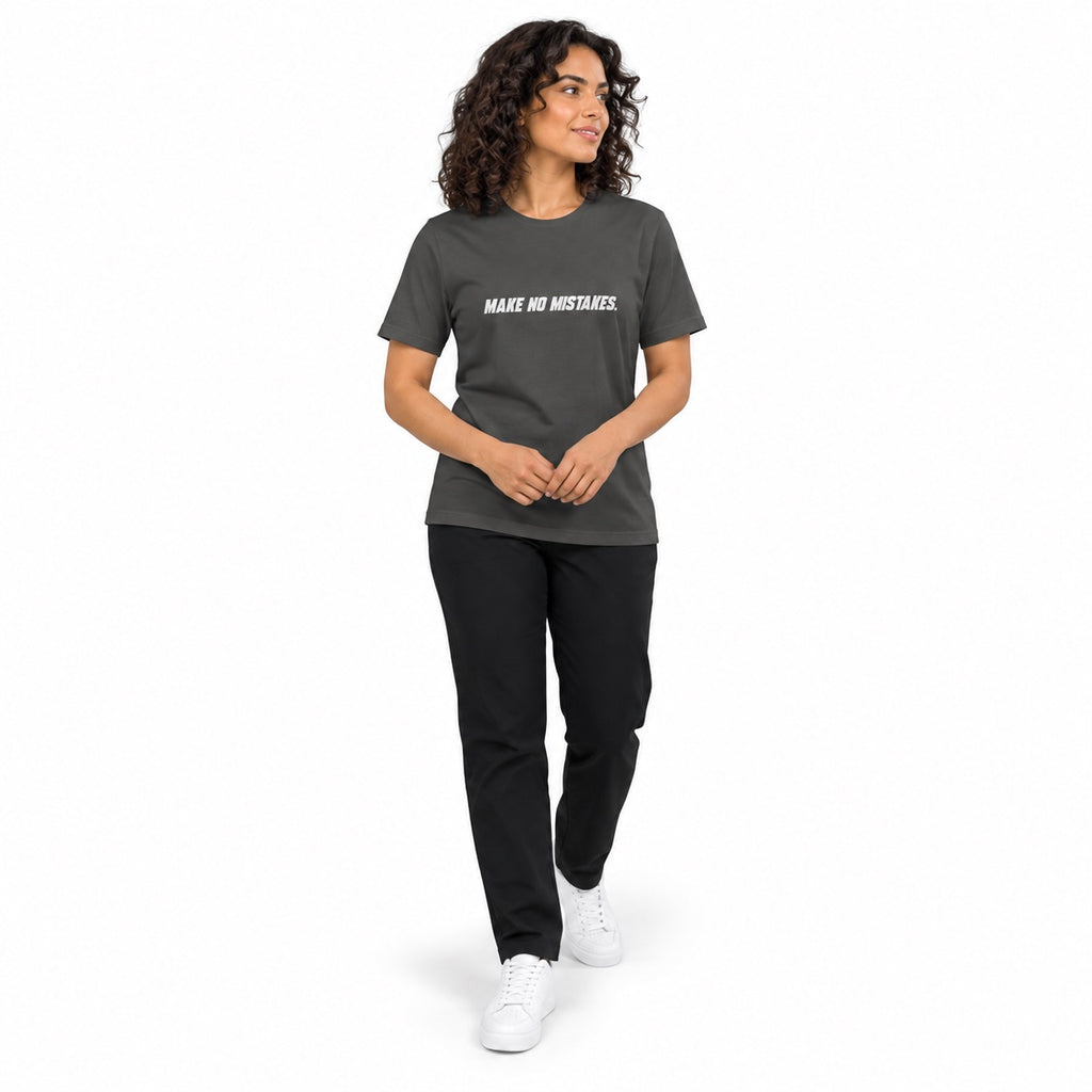 Full-body model wearing the asphalt MAKE NO MISTAKES. T-shirt with white chest print, stepping forward with hands loosely clasped at her waist on a white background.