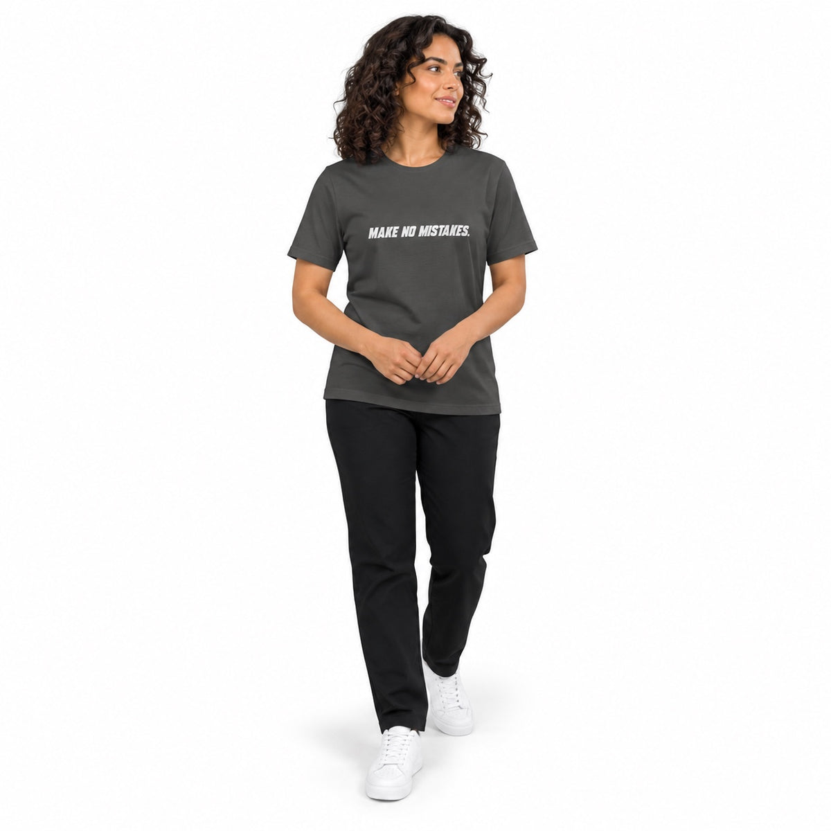 Full-body model wearing the asphalt MAKE NO MISTAKES. T-shirt with white chest print, stepping forward with hands loosely clasped at her waist on a white background.