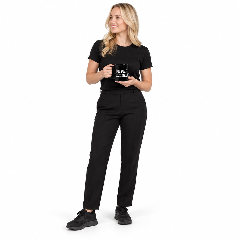 Full-body blonde model in black clothing holding the glossy black Super Intelligence mug with white two-line lettering facing forward, looking aside on a plain white background.